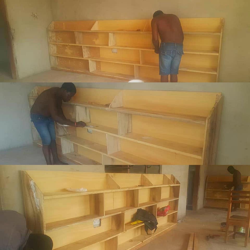 A local carpenter building and finishing wooden bookshelves for a school reading corner