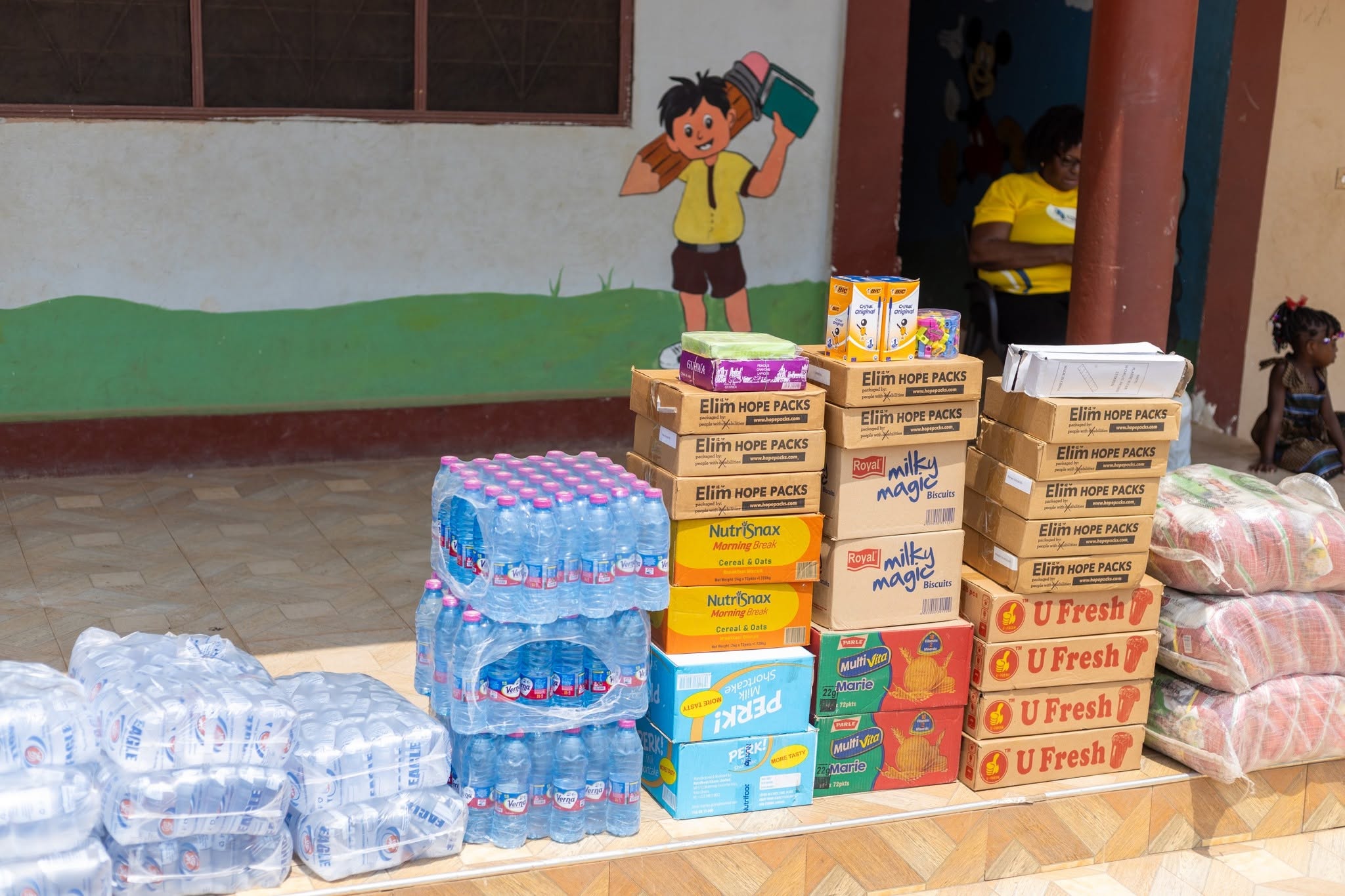 Stacks of drinking water, learning kits and food supplies outside a children's home