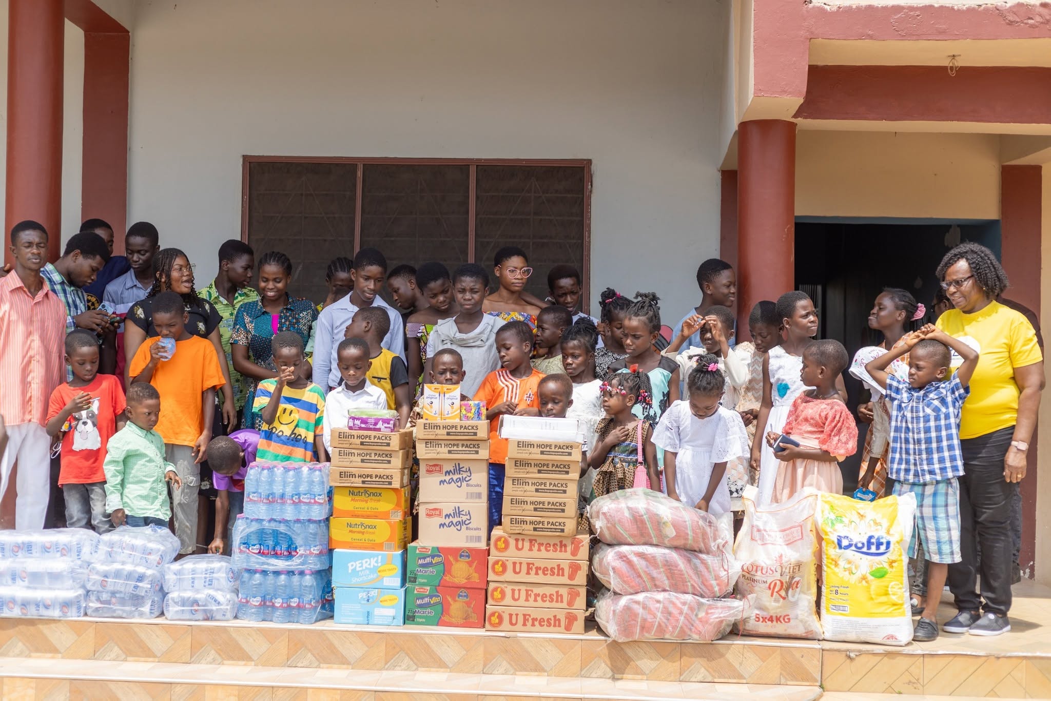 Children gathered beside drinking water and food supplies delivered during a community resilience outreach